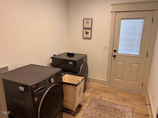 clothes washing area featuring baseboards, light wood-style flooring, and laundry area