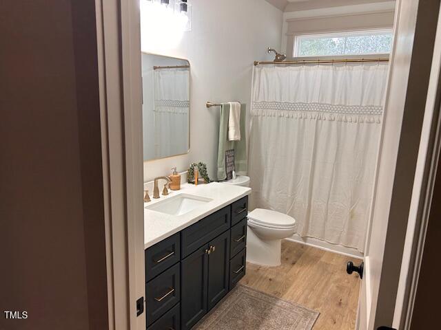 full bathroom with a shower with shower curtain, toilet, vanity, and wood finished floors