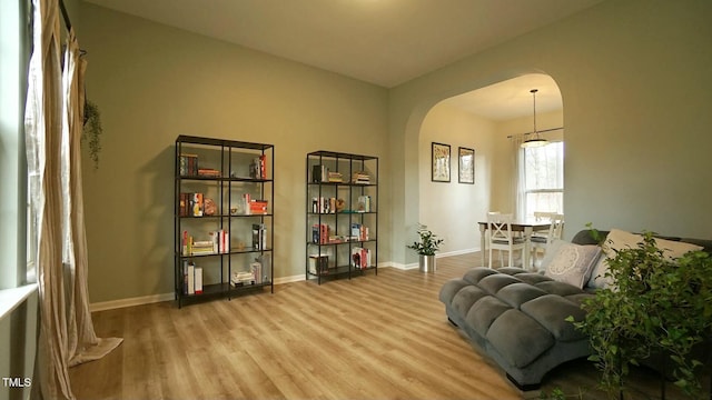 sitting room featuring wood finished floors, arched walkways, and baseboards