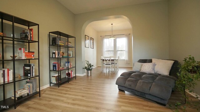 sitting room with wood finished floors, arched walkways, and baseboards