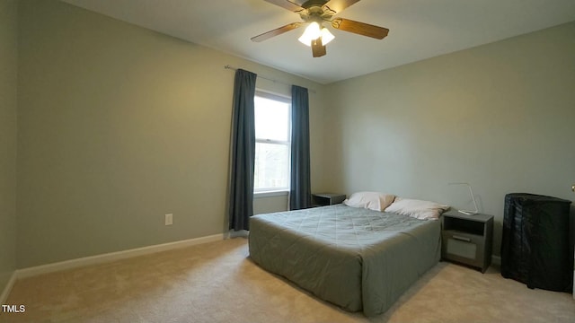 bedroom with light colored carpet, baseboards, and ceiling fan