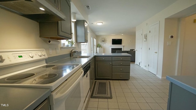 kitchen featuring a peninsula, light tile patterned flooring, a sink, under cabinet range hood, and white electric range