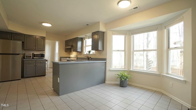 kitchen featuring light tile patterned floors, appliances with stainless steel finishes, and a wealth of natural light