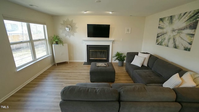 living area with a fireplace with flush hearth, wood finished floors, and baseboards