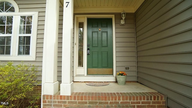 entrance to property featuring covered porch and brick siding