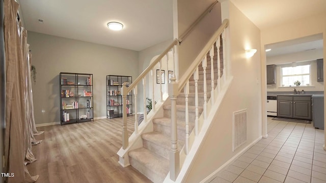 stairs with tile patterned floors, visible vents, and baseboards