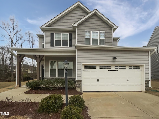 view of front of house featuring stone siding, covered porch, and driveway