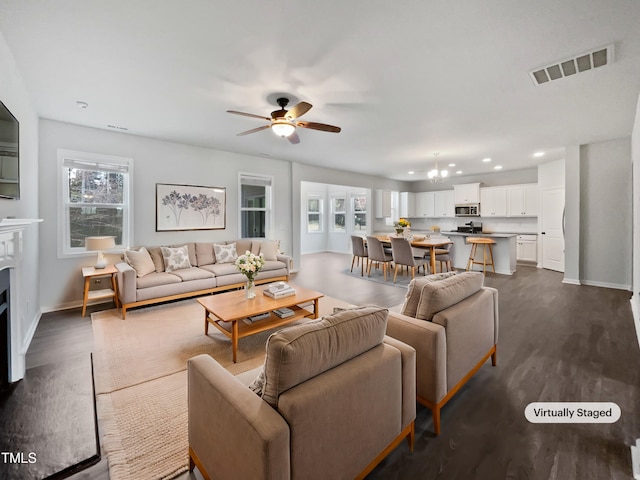 living area with a wealth of natural light, visible vents, dark wood-type flooring, and baseboards