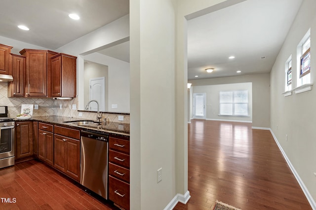 kitchen with dark wood finished floors, backsplash, appliances with stainless steel finishes, and a sink