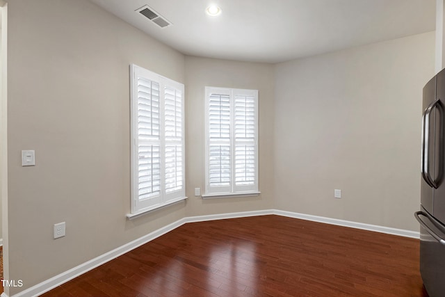 unfurnished room featuring visible vents, wood-type flooring, and baseboards