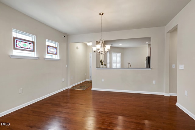 empty room featuring recessed lighting, baseboards, a notable chandelier, and hardwood / wood-style floors