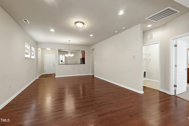 unfurnished living room with dark wood-style floors, visible vents, and a chandelier