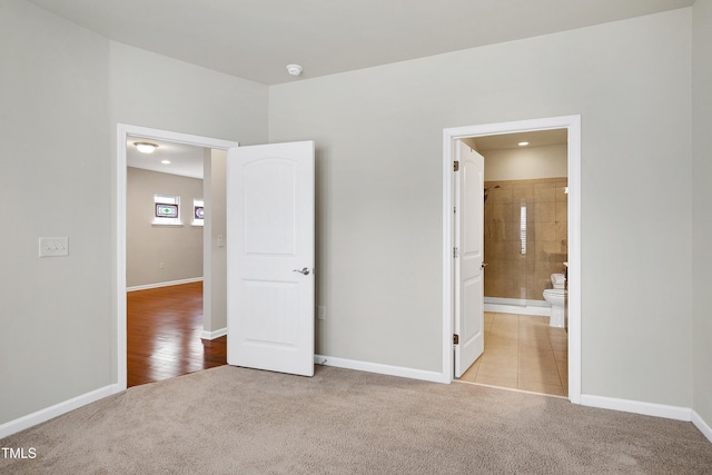 unfurnished bedroom featuring carpet flooring, ensuite bathroom, and baseboards