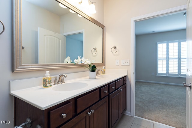 bathroom with tile patterned flooring, double vanity, baseboards, and a sink