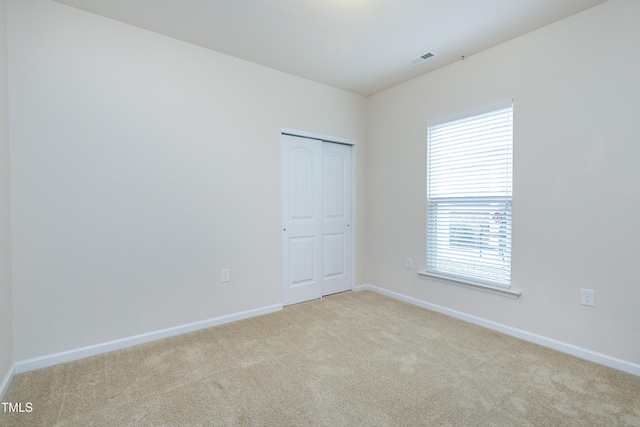 carpeted spare room featuring visible vents and baseboards