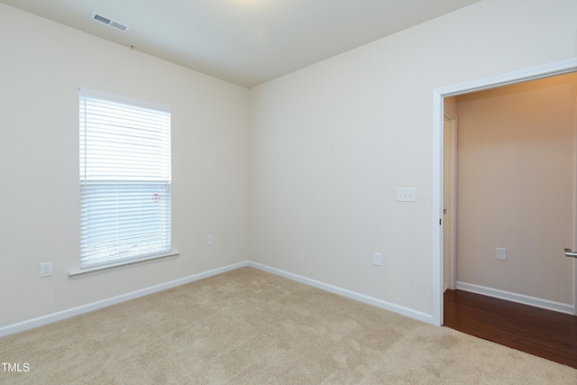 empty room featuring carpet, visible vents, and baseboards