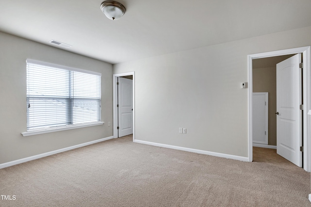 carpeted spare room with visible vents and baseboards