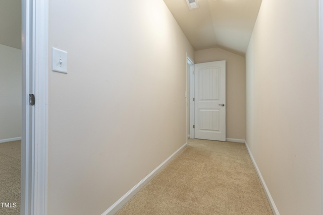 hall with lofted ceiling, light colored carpet, baseboards, and visible vents