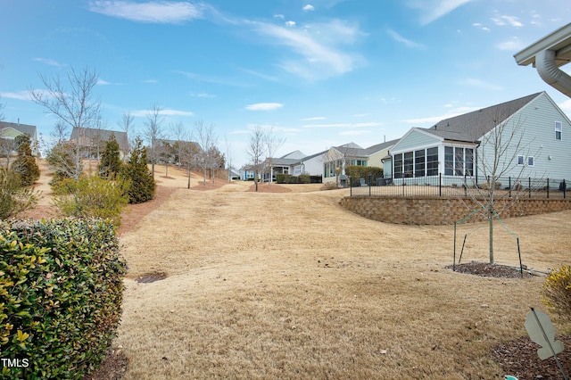 view of yard featuring fence, a residential view, and a sunroom