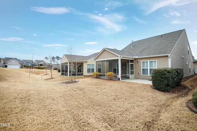 rear view of house featuring a sunroom and a shingled roof