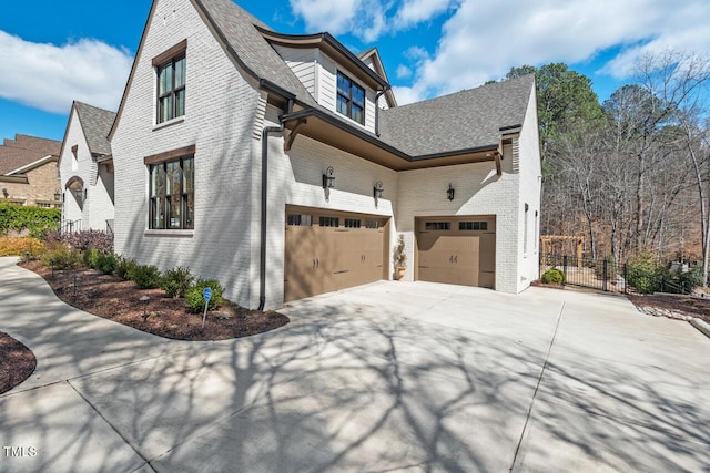 view of home's exterior with brick siding, an attached garage, concrete driveway, and fence