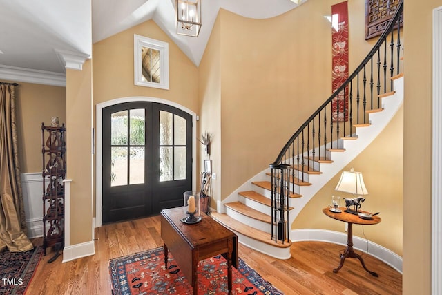 entryway featuring high vaulted ceiling, wood finished floors, french doors, baseboards, and stairs