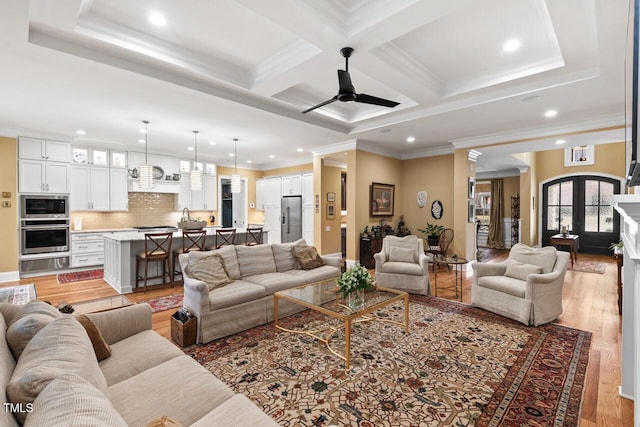 living room with beamed ceiling, coffered ceiling, light wood-type flooring, and ornamental molding