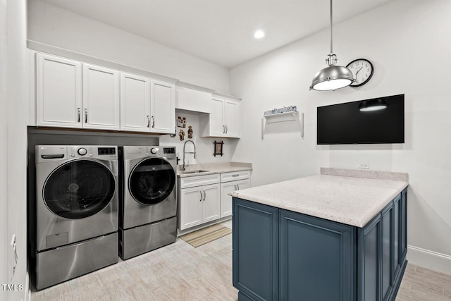 washroom with washing machine and clothes dryer, cabinet space, light wood-type flooring, and a sink