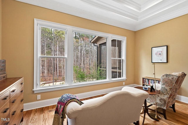 living area featuring visible vents, a raised ceiling, ornamental molding, wood finished floors, and baseboards