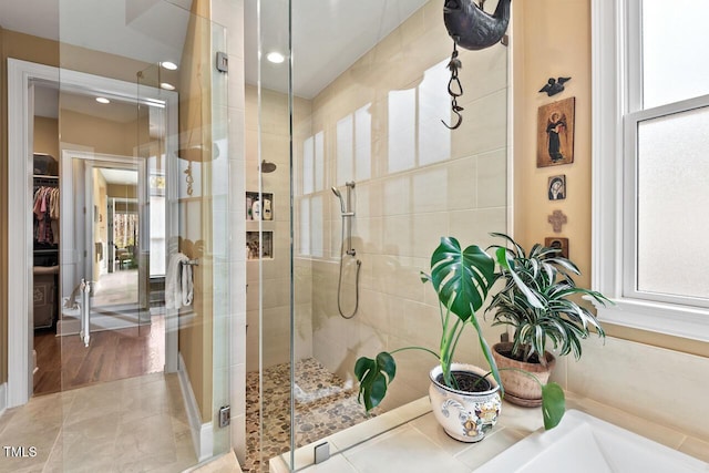 bathroom featuring a spacious closet, a healthy amount of sunlight, and a shower stall