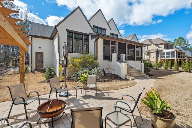 view of patio featuring fence, an outdoor fire pit, a pergola, and a sunroom