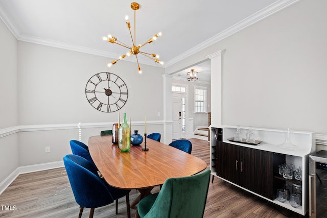 dining area featuring decorative columns, wood finished floors, and ornamental molding