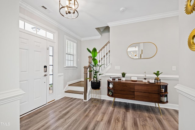 entrance foyer with an inviting chandelier, wood finished floors, and ornamental molding