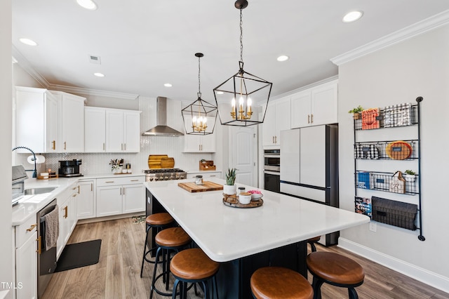 kitchen featuring a breakfast bar area, wall chimney exhaust hood, crown molding, and freestanding refrigerator