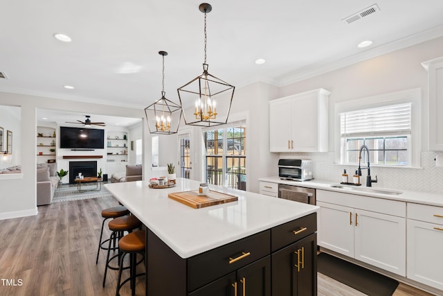 kitchen with a sink, white cabinets, a fireplace, and ornamental molding