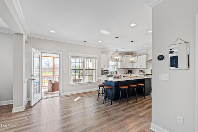 kitchen with white cabinets, crown molding, light countertops, and a kitchen bar