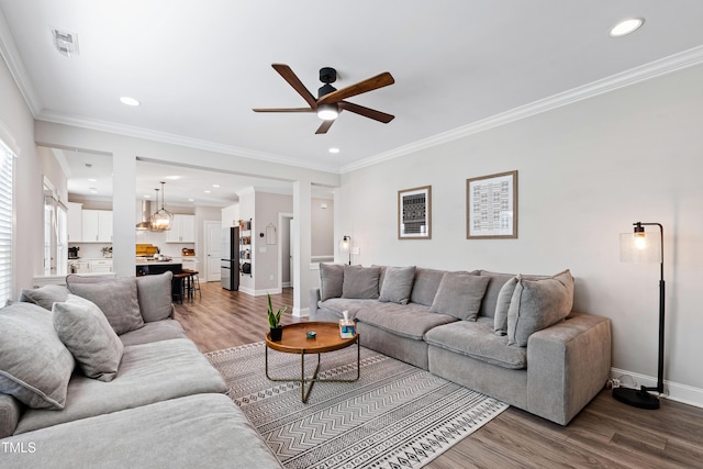 living area featuring visible vents, crown molding, baseboards, recessed lighting, and wood finished floors