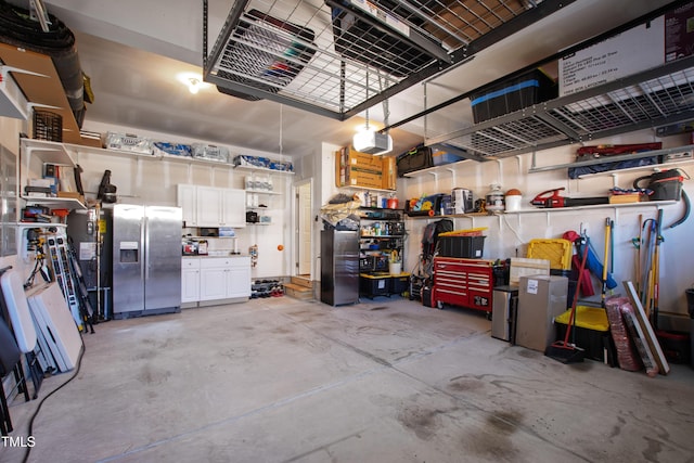 garage featuring a workshop area, a garage door opener, and stainless steel refrigerator with ice dispenser