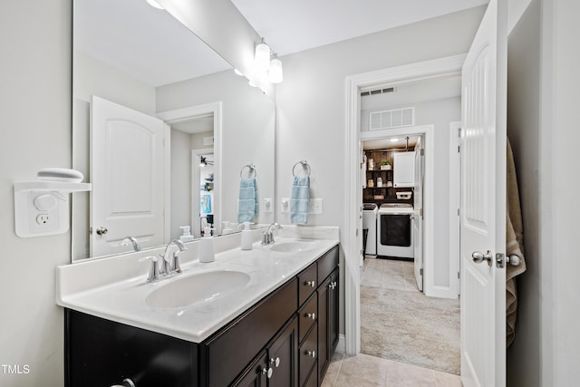 full bath featuring double vanity, separate washer and dryer, visible vents, and a sink