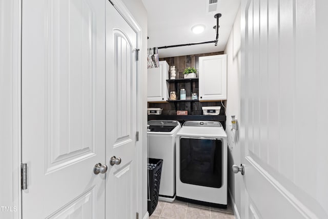 laundry area featuring light tile patterned floors, visible vents, cabinet space, and washing machine and dryer