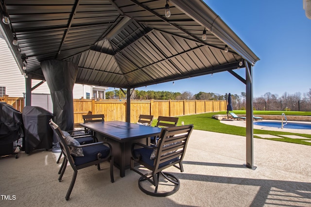 view of patio with a gazebo, a grill, outdoor dining area, and fence