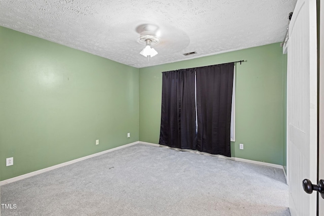 carpeted empty room featuring visible vents, a textured ceiling, and baseboards