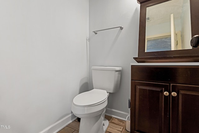 half bath featuring baseboards, toilet, wood finished floors, and vanity