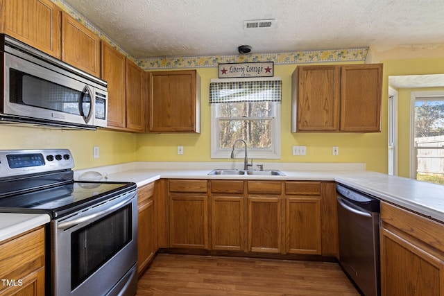 kitchen featuring visible vents, dark wood finished floors, a sink, stainless steel appliances, and a textured ceiling