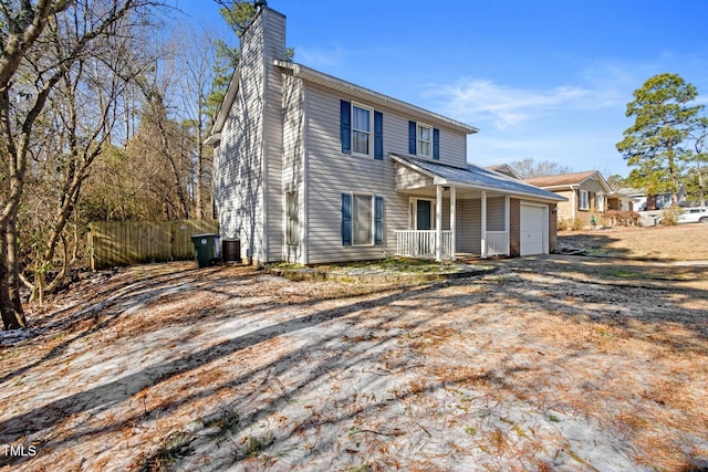 view of front of home with central air condition unit, a porch, fence, a garage, and a chimney