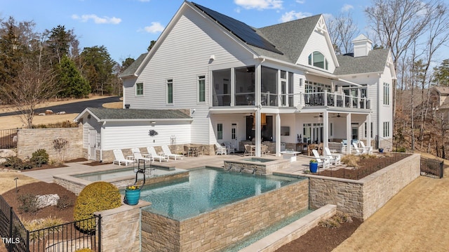 rear view of property featuring solar panels, fence, a patio, a sunroom, and a ceiling fan