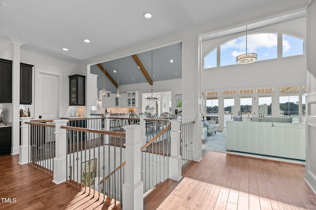 hall with an upstairs landing, light wood-type flooring, a wealth of natural light, and a chandelier