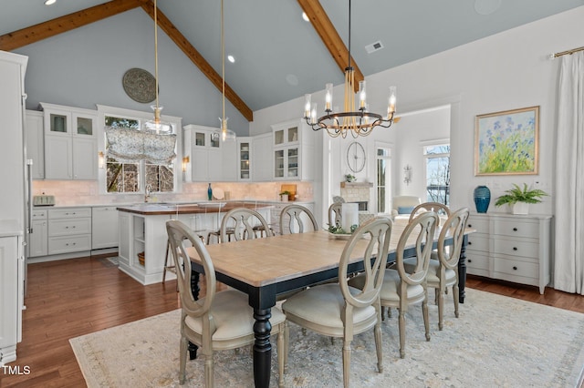 dining area with visible vents, hardwood / wood-style floors, beam ceiling, an inviting chandelier, and high vaulted ceiling