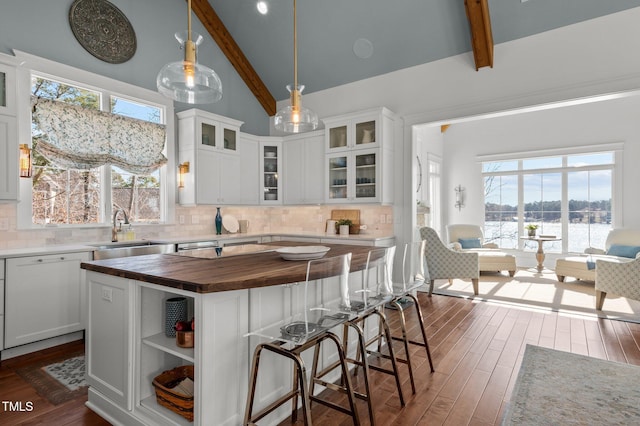 kitchen featuring beam ceiling, high vaulted ceiling, butcher block countertops, a sink, and dark wood-style floors