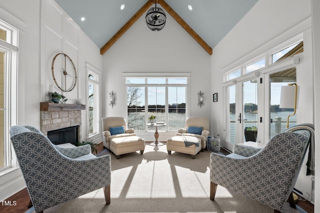 living room featuring beamed ceiling, a fireplace, a water view, and high vaulted ceiling